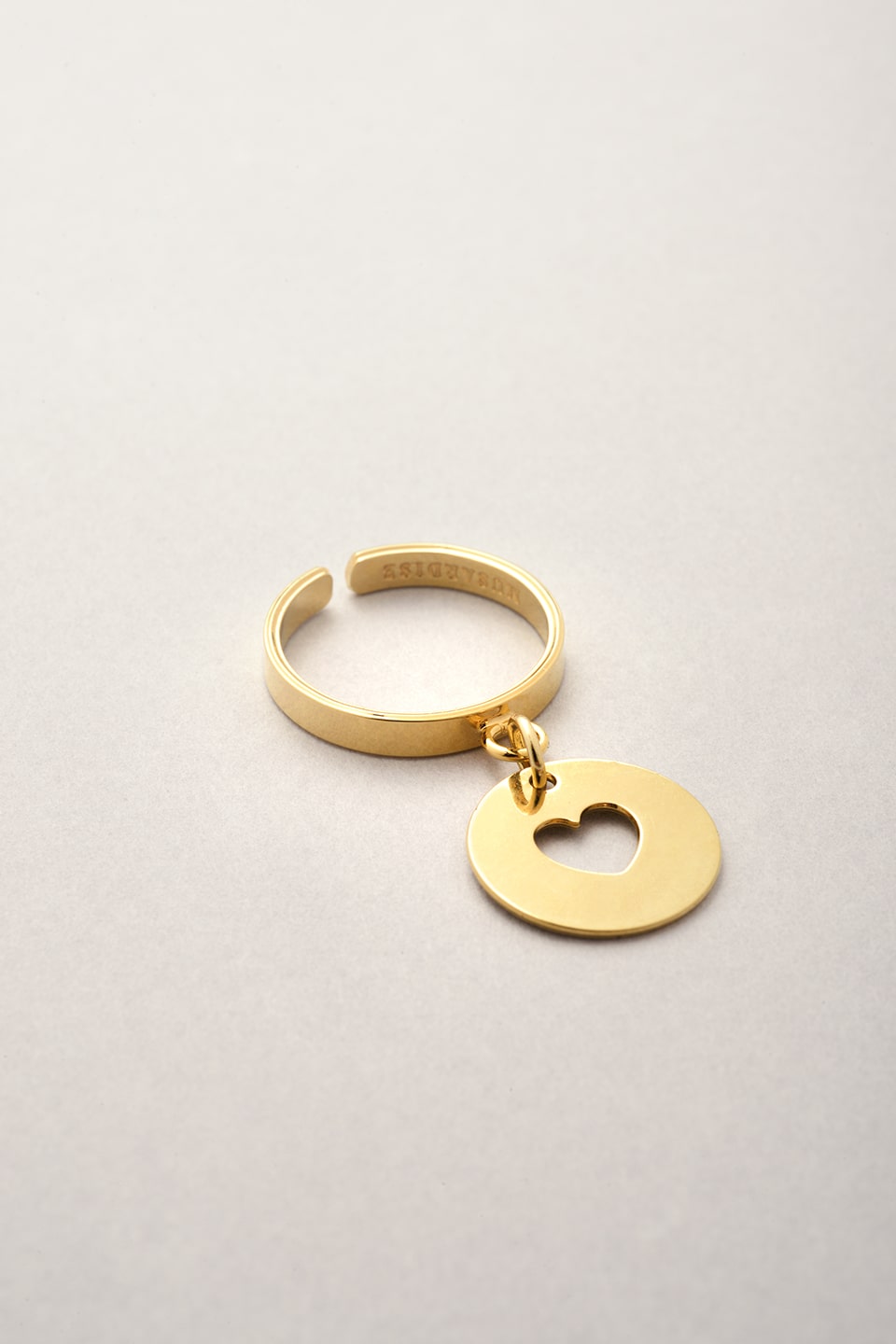 La bague fine dorée coeur de Musardise. Une bague made in France réglable avec son pendentif médaille coeur évidé. 