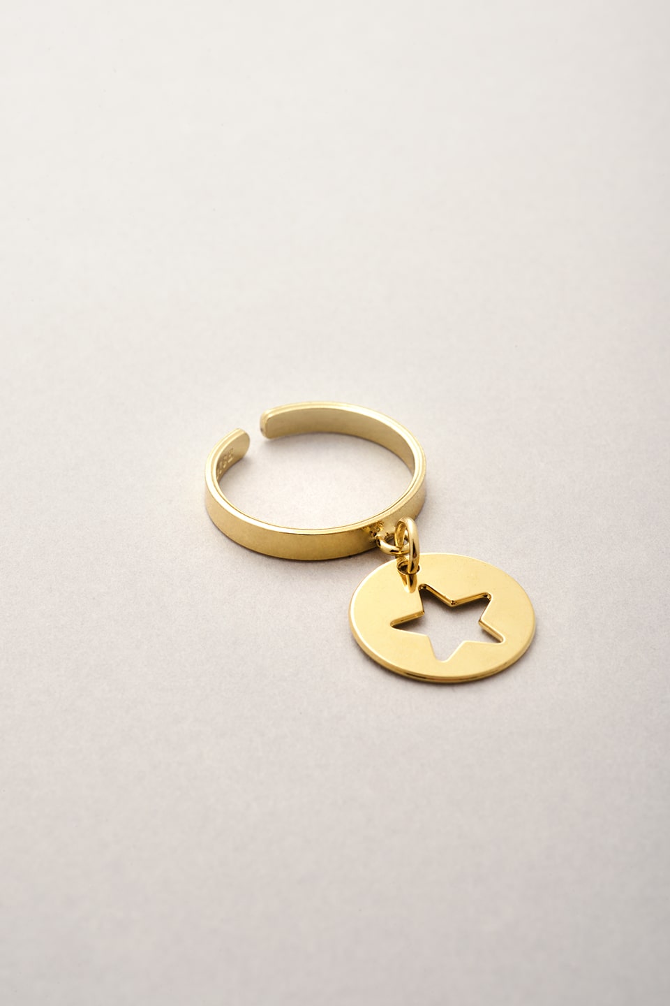 La bague fine dorée et réglable de Musardise avec son pendentif médaille en forme d'étoile évidée.