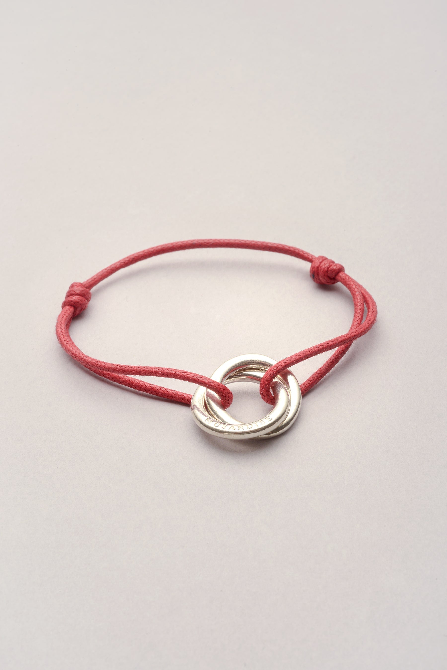 Ce bijou est composé d'un pendentif représentant deux anneaux entrelacés. Ajustable, il est possible de régler la taille en faisant coulisser les noeuds coulissants. En plus, il est personnalisables : vous pouvez choisir la couleur du bracelet ! 