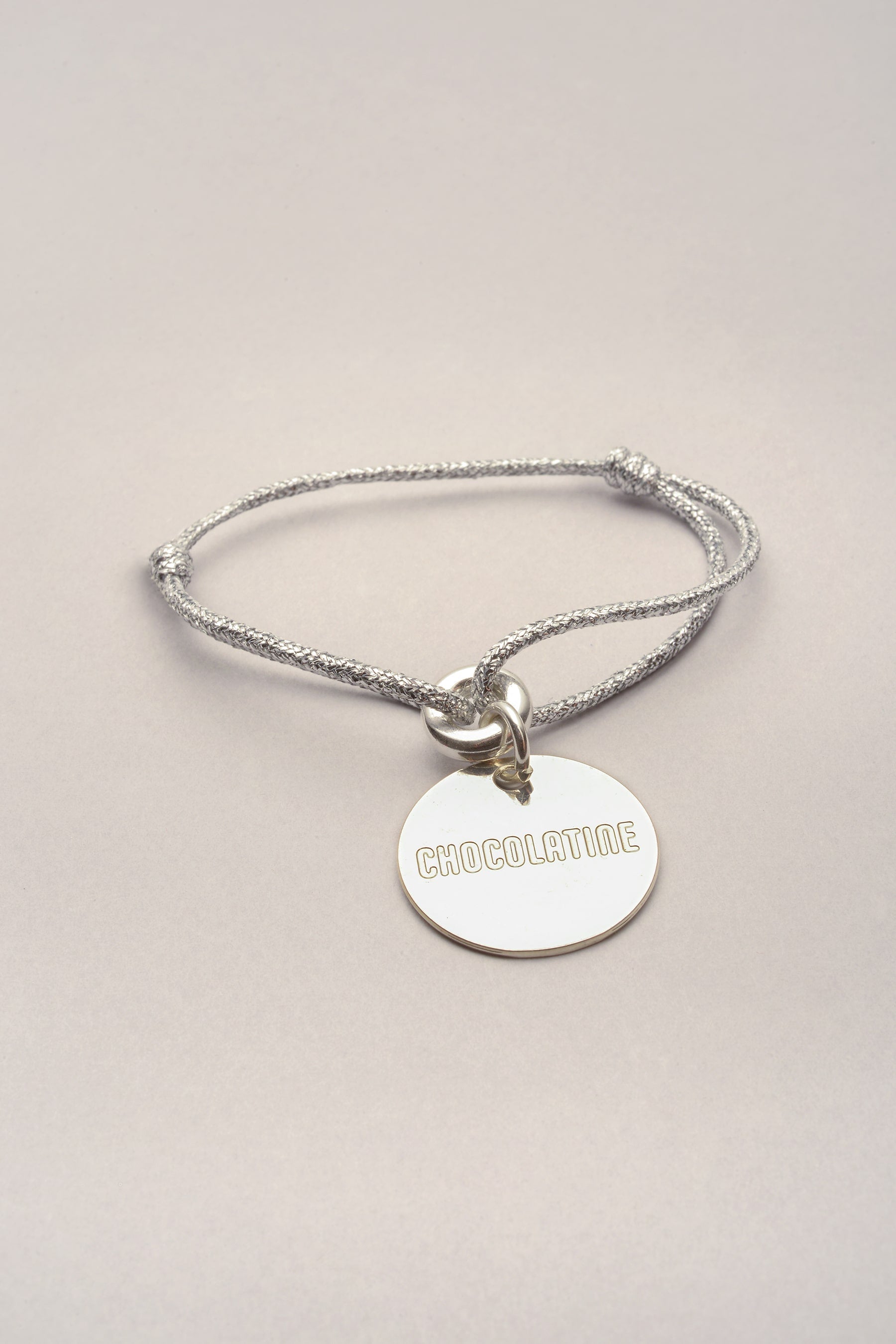 ce bracelet est composé d'un cordon de coton coloré et d'une médaille argentée sur laquelle est gravée "chocolatine". 