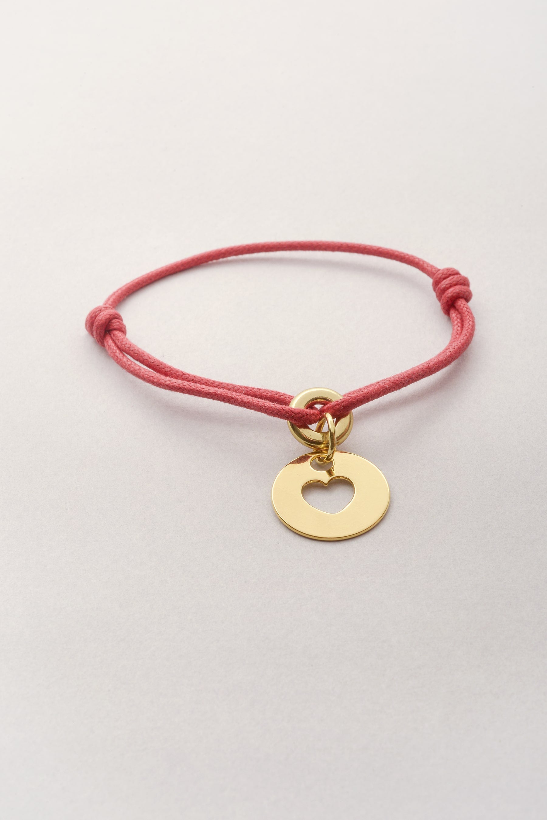 Ce Bracelet Liv médaille Coeur doré avec cordon de coton coloré est fabriqué en France. Ajustable grâce à deux noeuds coulissants, ce bijou fantaisie doré convient à tous les poignets. 