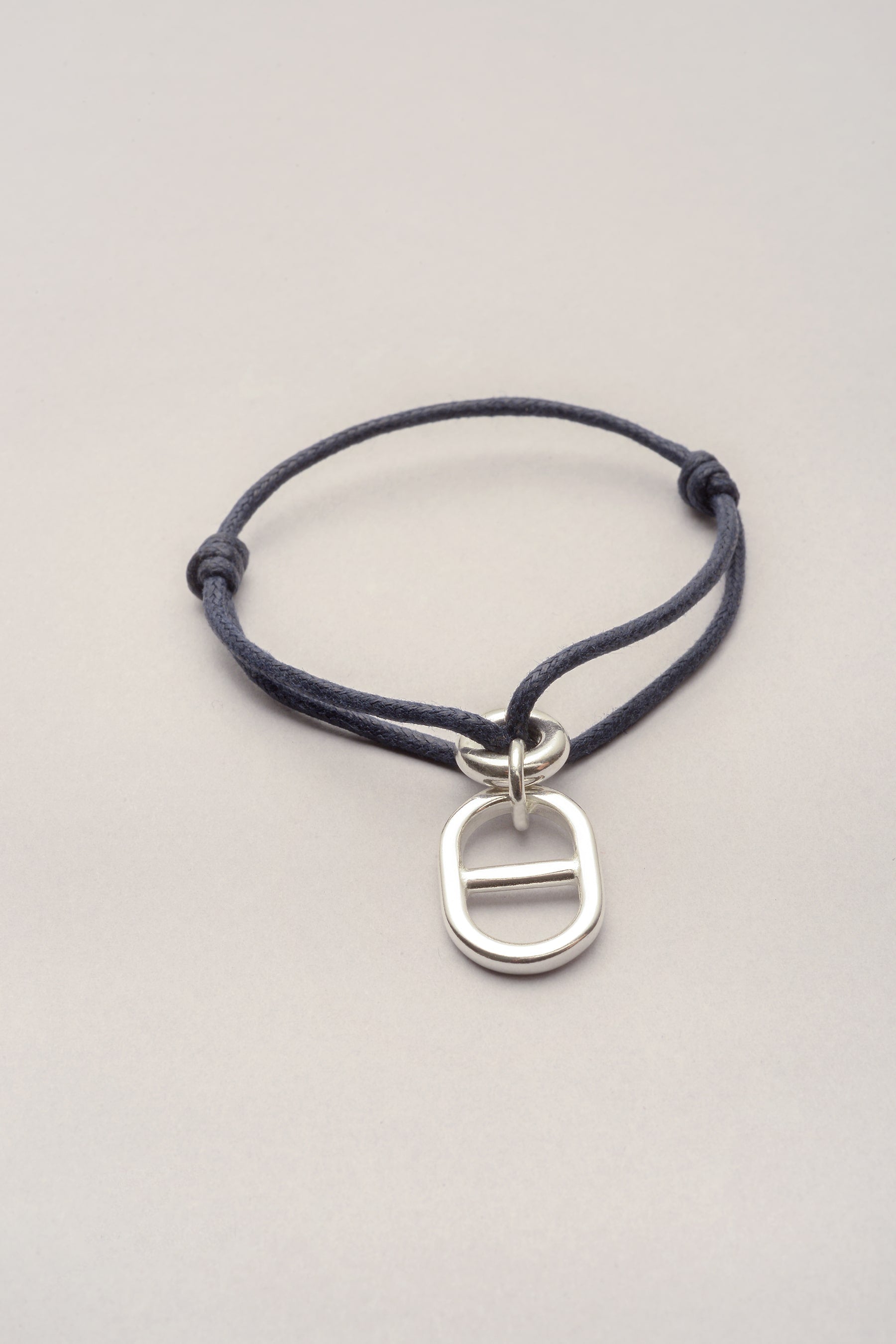 Ce bracelet est composé d'un cordon de coton coloré et d'un pendentif maille marine. Ce bijou s'adapte à toutes les morphologies grâce à deux noeuds coulissants. 