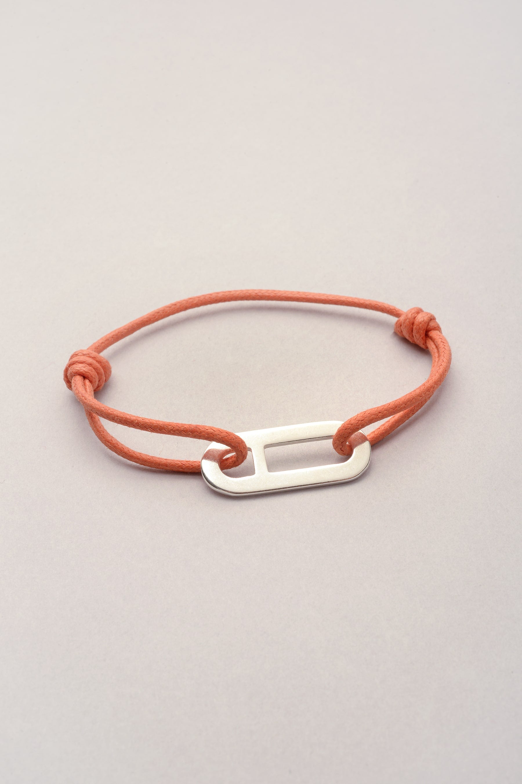 Ce bijou est composé d'un pendentif "Noé" représentant une maille asymétrique et d'un cordon de coton coloré. 