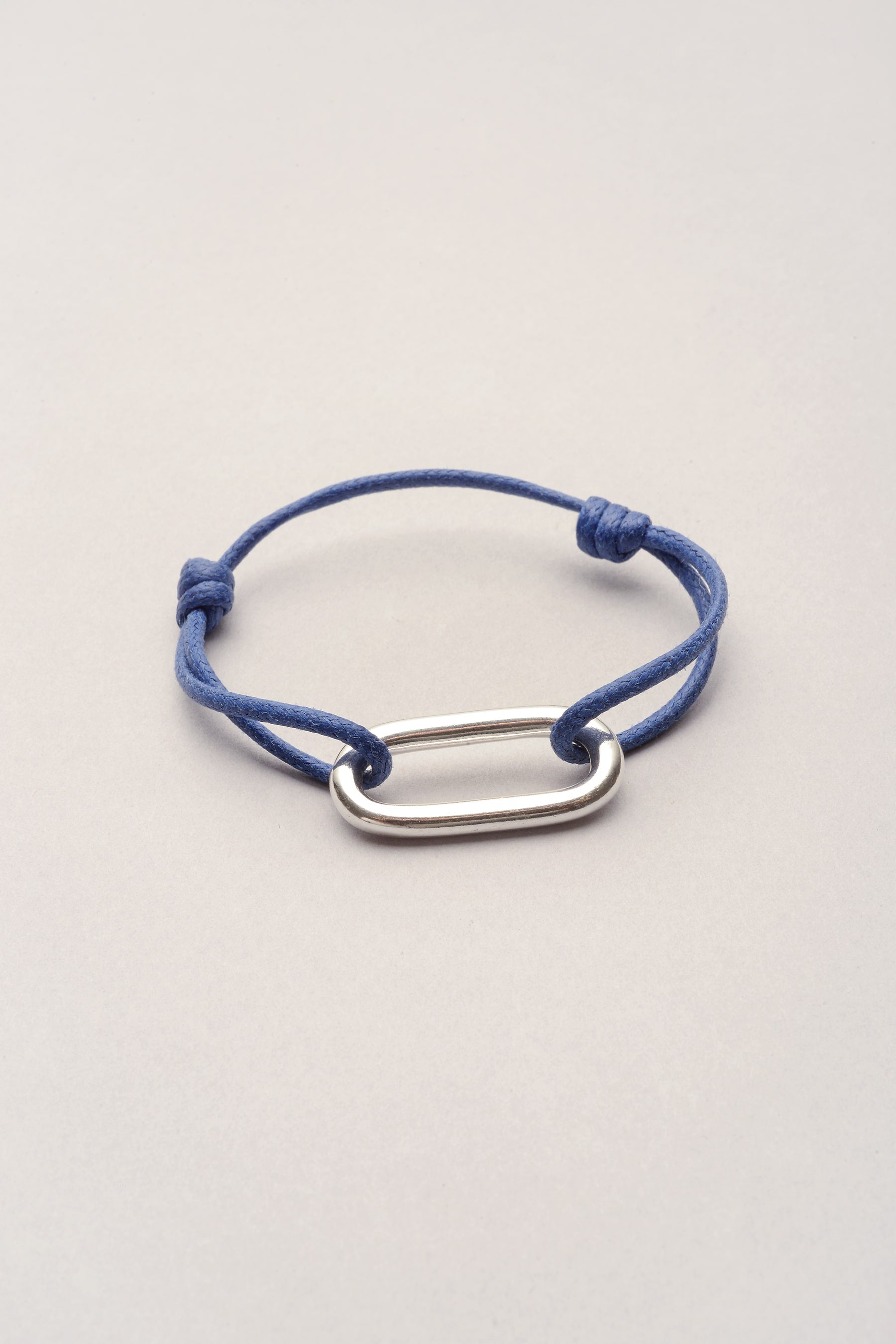 ce bracelet est composé d'un cordon de coton coloré et d'un pendentif oval et rectangulaire. Mixte, ce bijou fantaisie convient pour femme et pour homme. 