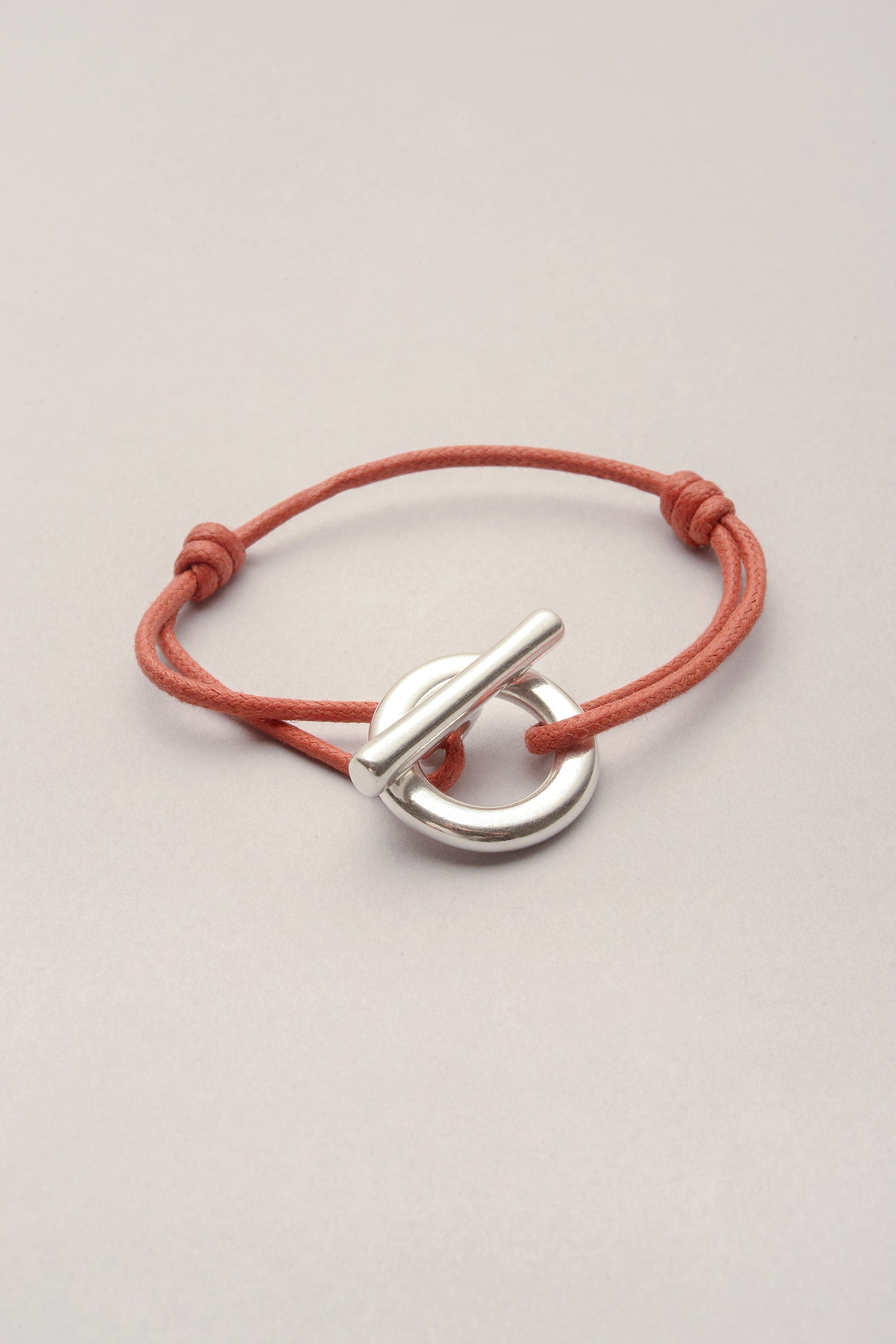 Ce bracelet est composé d'un cordon de coton coloré et d'un fermoir en T épais. 