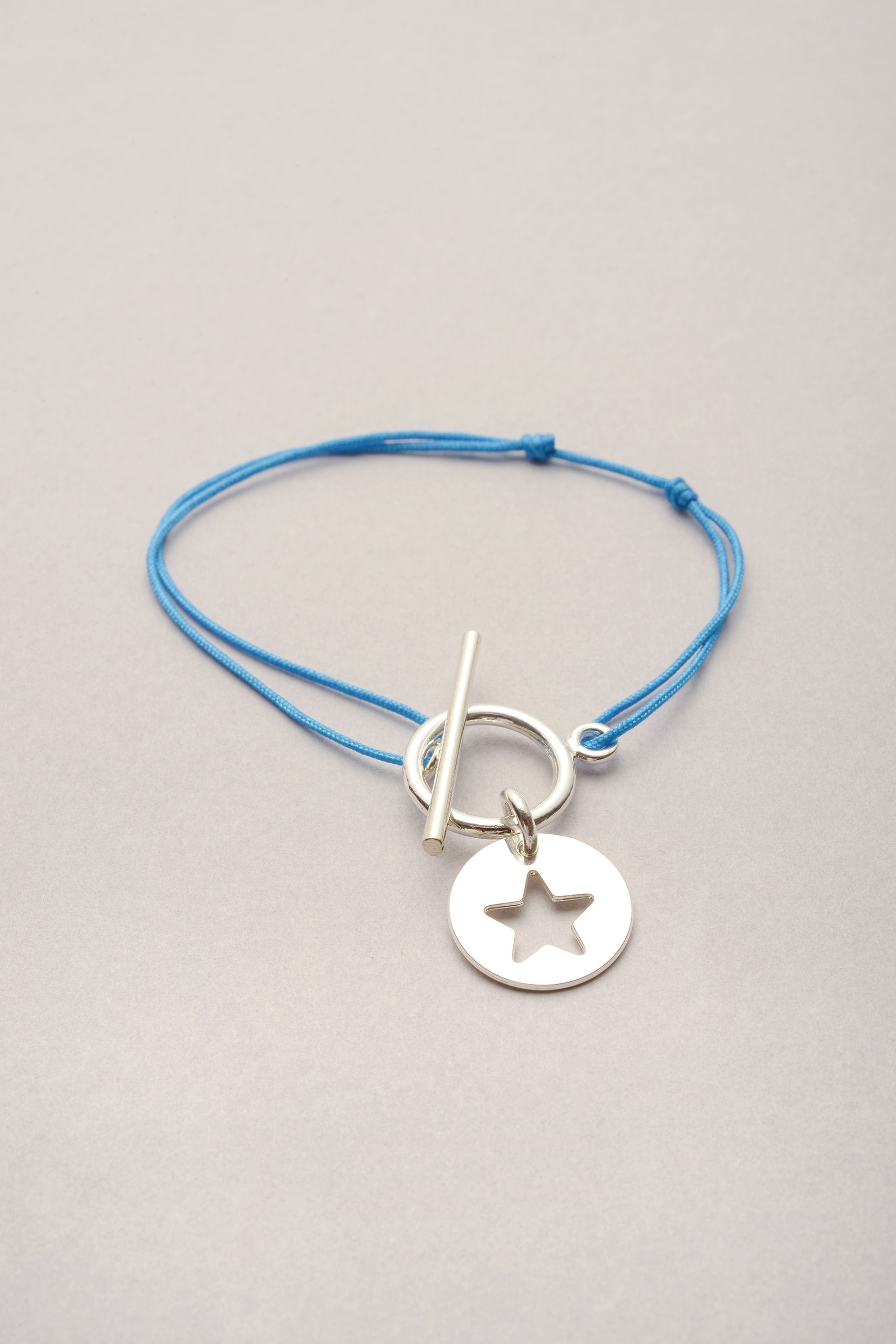 e bracelet Lou Médaille étoile argenté est un bijou fantaisie composé d’une médaille argentée montée sur un cordon réglable grâce à deux nœuds coulissants. 