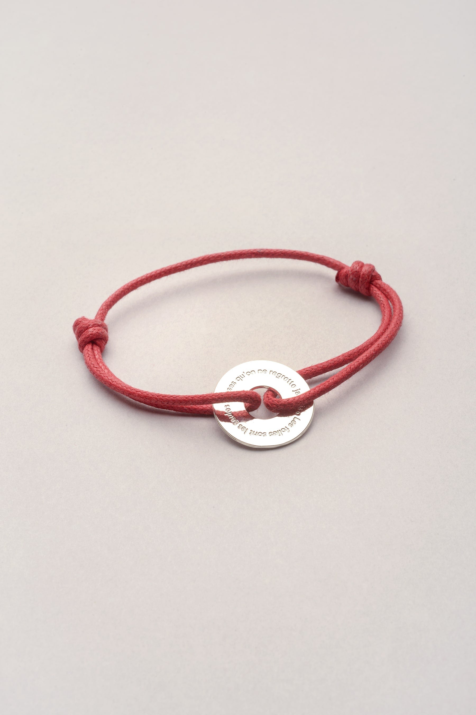 Ce bracelet est composé d'un pendentif en forme de rondelle argentée, sur lequel est inscrit la citation suivante : "les folies sont les seules choses qu'on ne regrette jamais". Mixte et réglable, il est idéal comme cadeau à une personne qu'on aime. 