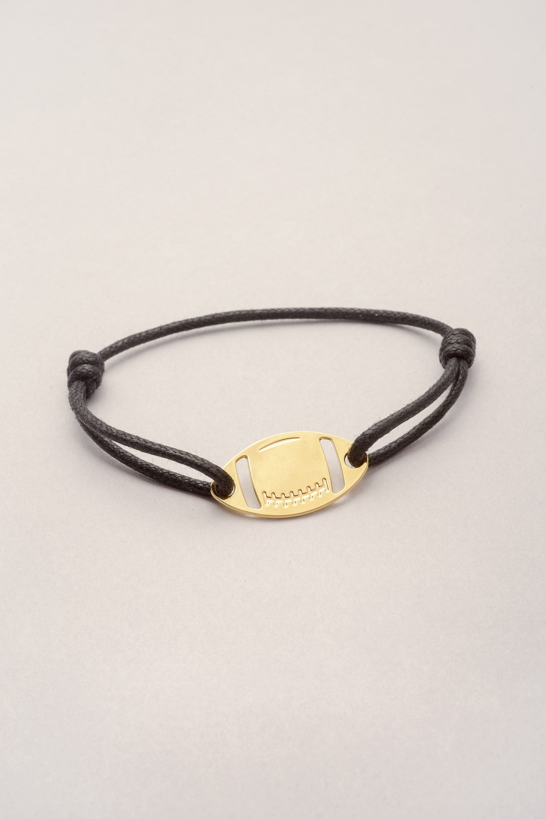 Ce bijou est composé d'un pendentif ballon de rugby doré et d'un cordon de coton coloré réglable. Il s'agit d'un pendentif avec deux perçages, le pendentif ballon de rugby est collé au poignet. De plus, le cordon peut se personnaliser dans la couleur de votre choix. Par exemple, si vous soutenez le Stade Toulousain, on peut choisir en couleur le rouge ou le noir. Ce bracelet est mixte, il convient pour homme et femme. C'est un cadeau parfait pour les fans de Rugby ! 