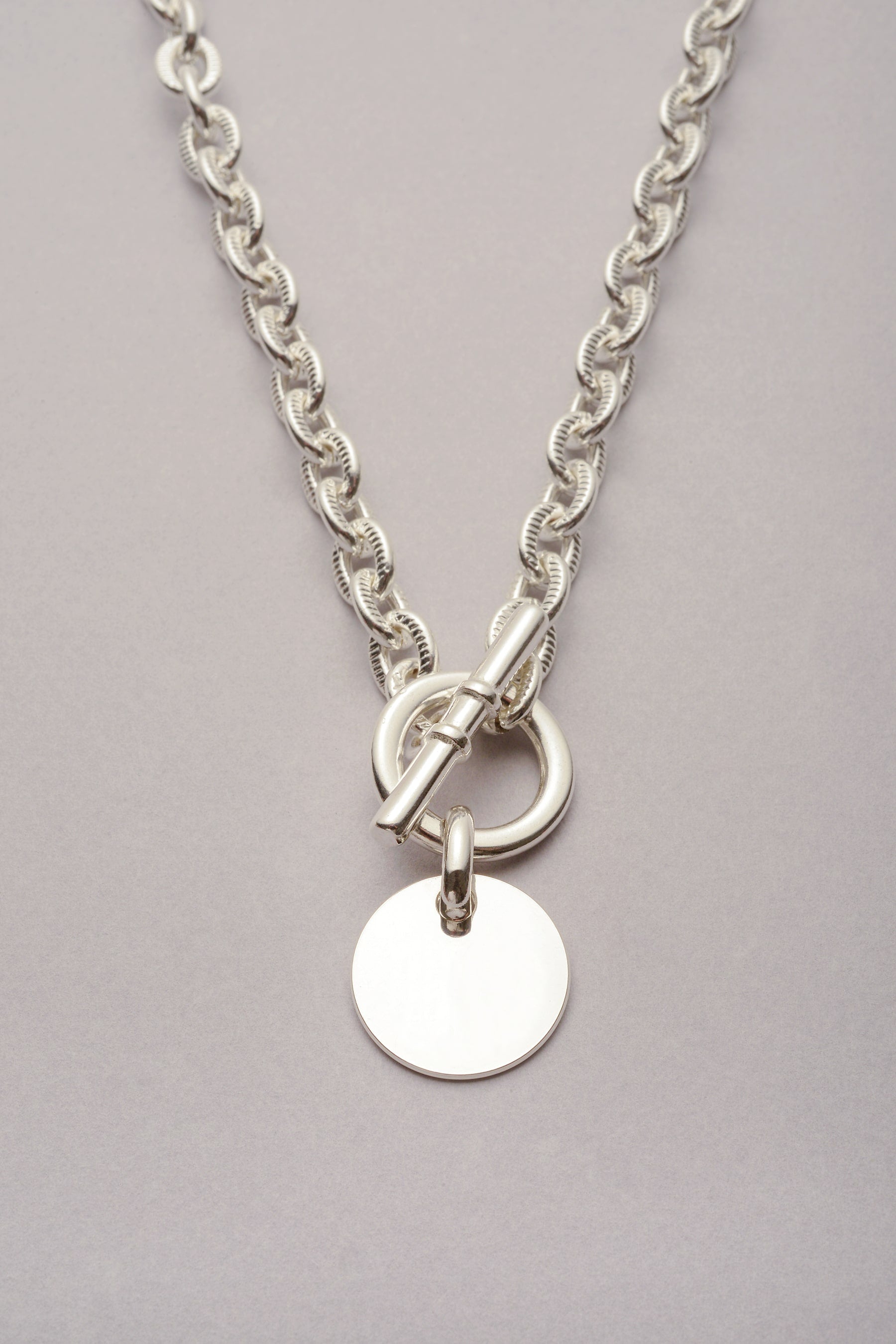 Collier Scarlett Médaille avec chaîne argenté. Ce bijou fabriqué en France se compose d'un fermoir en T et d'une médaille argentée. 