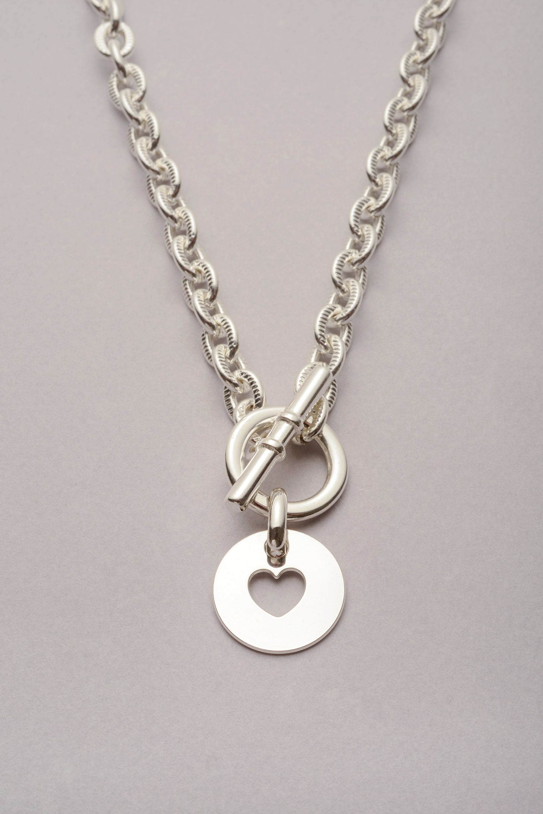 Collier Scarlett médaille Coeur argenté. Bijou composé d'une chaîne, f'un fermoir en T et d'un pendentif coeur. 