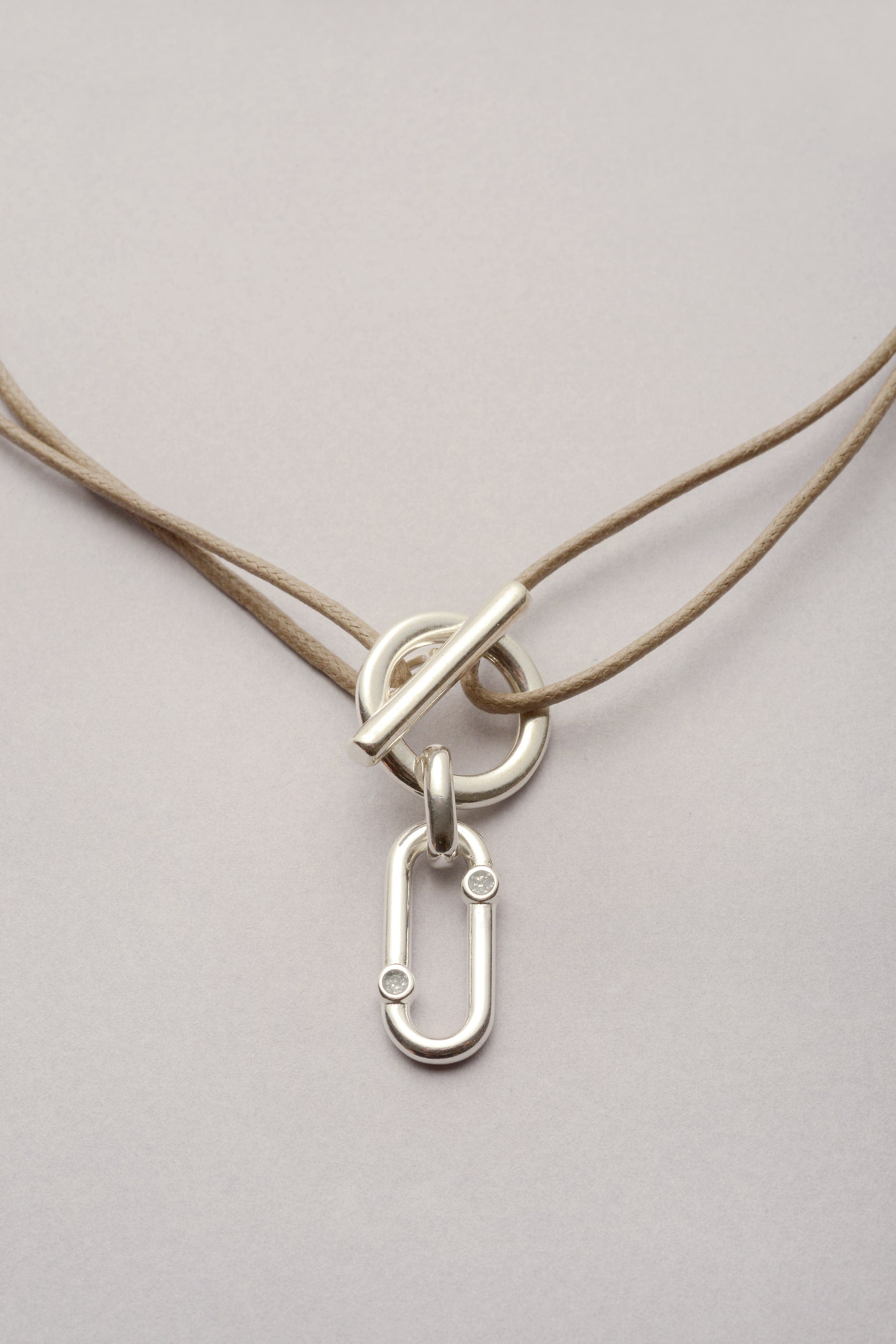 Ce collier est composé d'un pendentif oval orné de deux strass en résine argenté. Le oendentif est apposé sur un fermoir en T pour rendre pratique à porter le bijou : on peut l'ouvrir et le fermer sans passer par la tête. Le cordon est réglable, on peut donc choisir la longueur. Coloré, vous pouvez aussi choisir la couleur ! 