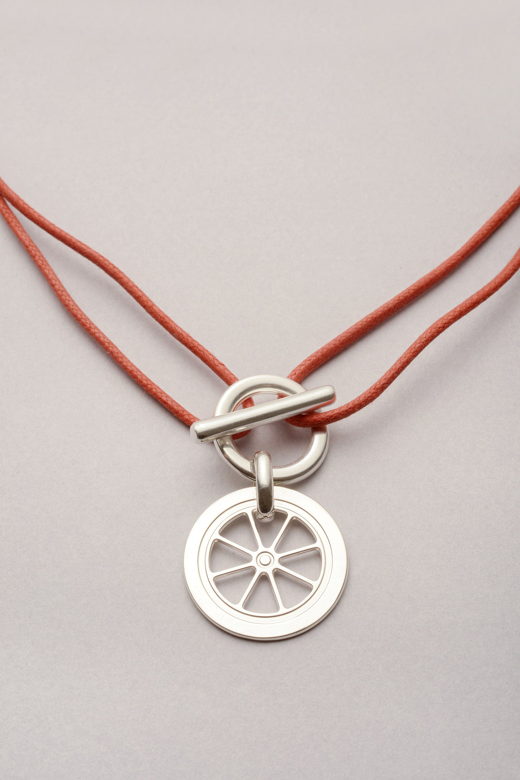 Ce collier est composé d'un pendentif en forme de roue, d'un fermoir en T et d'un cordon de coton coloré réglable. En fait, le pendentif roue a été inspiré du triporteur à Bijoux Musardise. C'est l'une des premières véritables créations Musardise ! 