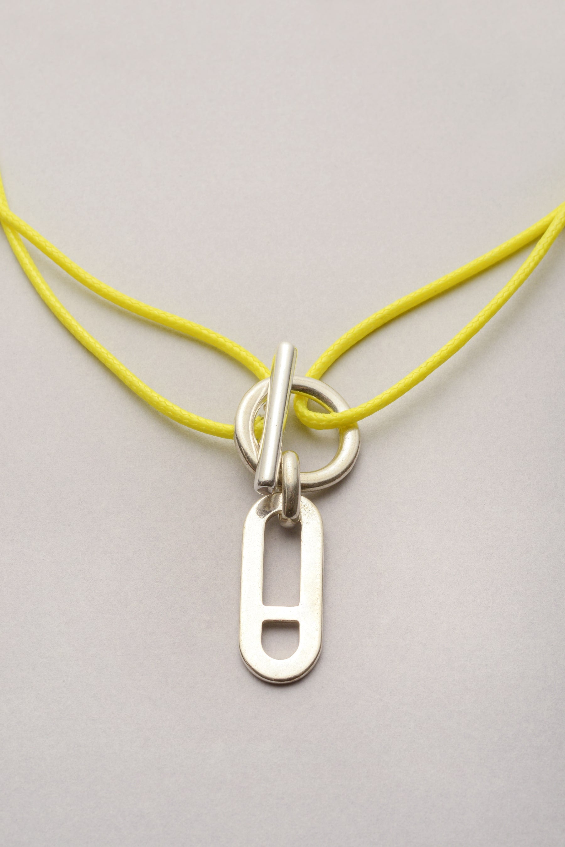 Ce collier est composé d'un cordon coloré et d'un fermoir en T avec un pendentif maille "Noé". L'attache est un fermoir en T, ce qui permet de mettre et enlever facilement le bijou au quotidien. 