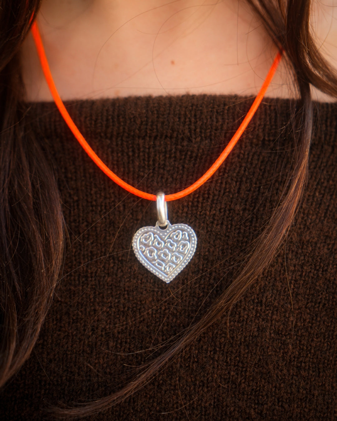 Collier argenté avec pendentif cœur motif léopard, monté sur un cordon coloré réglable.