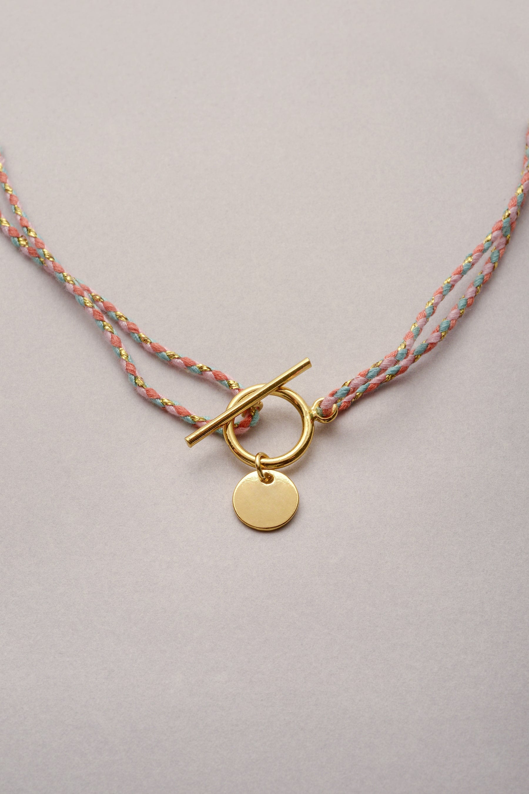 Le collier doré en cordon tressé coloré de Musardise avec son fermoir fin en T, disponible en plusieurs coloris. Cordon réglable et personnalisable