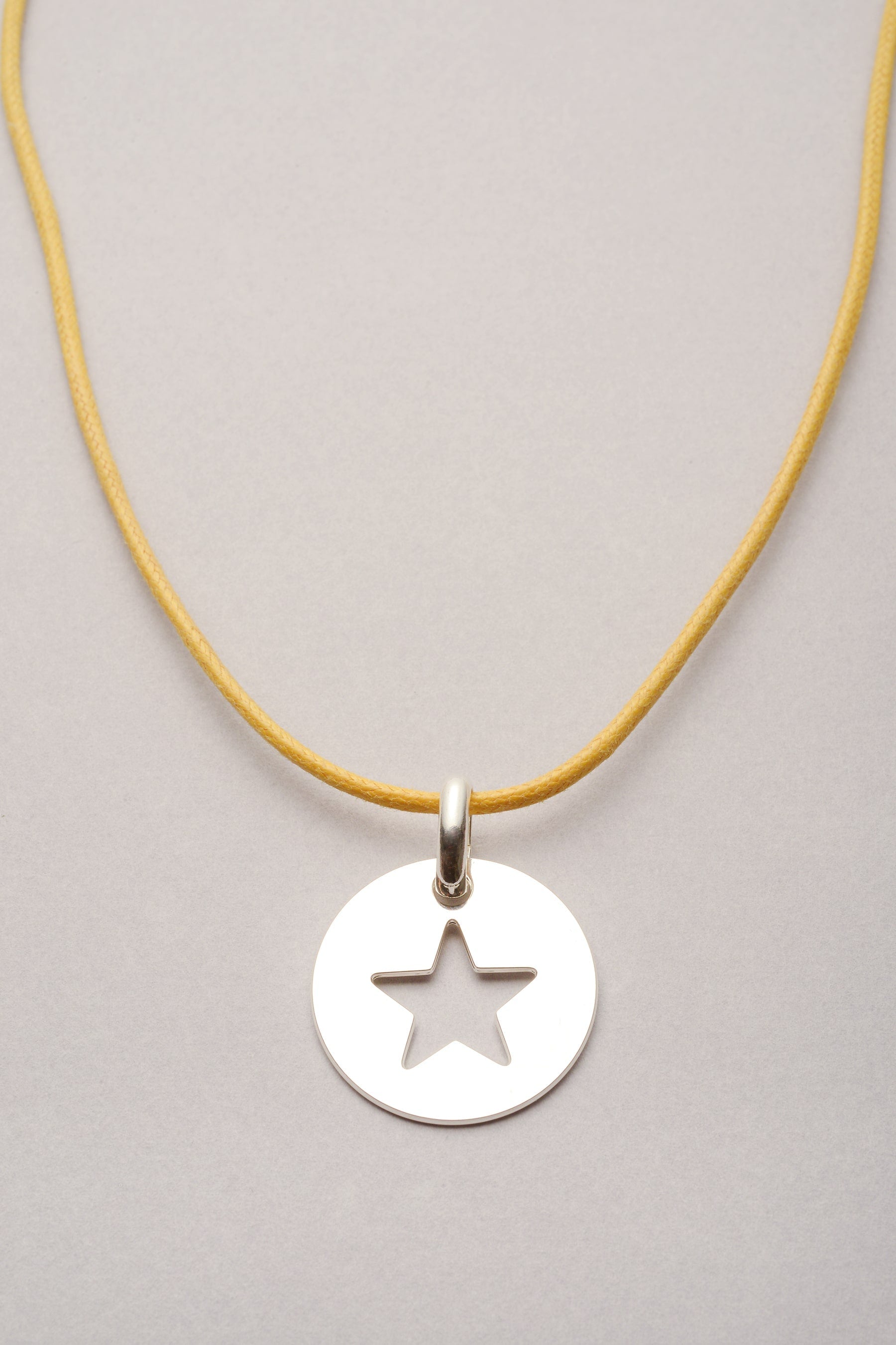 Ce collier est composé d'un cordon coloré réglable et d'une médaille étoile évidée argenté. Ce bijou est fabriqué en France, et est une idée de cadeau idéal pour femme. 
