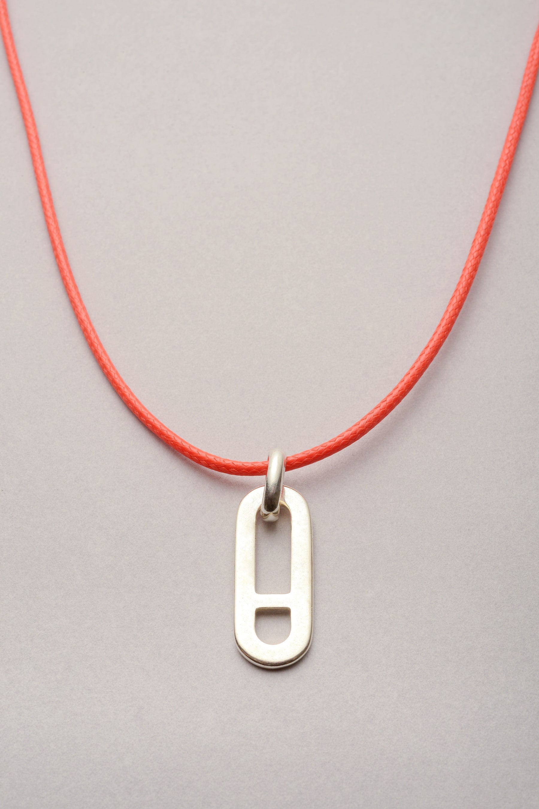 Ce collier se compose d'un pendentif maille asymétrique "Noé" et d'un cordon de coton coloré ajustable. 