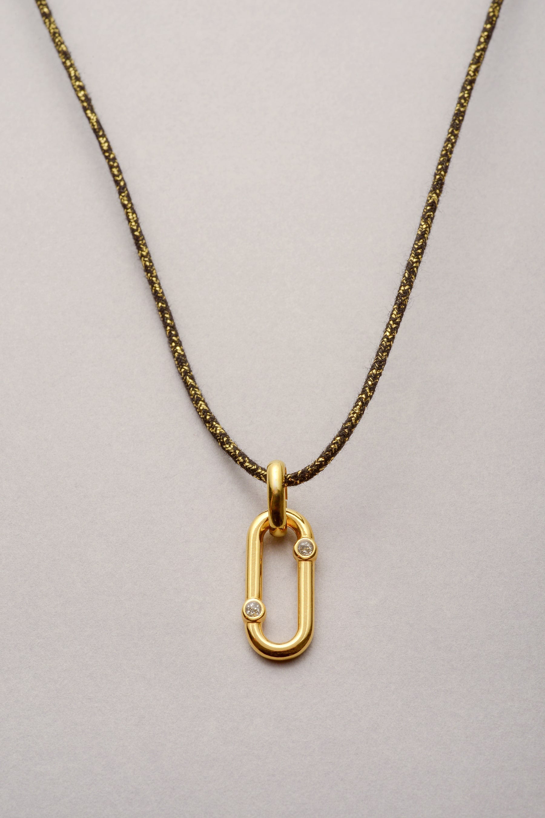 Ce collier est composé d'un cordond e coton coloré et d'un pendentif oval orné de deux strass asymétrique. Ce bijou est ajustable grâce à ses deux noeuds coulissants. 