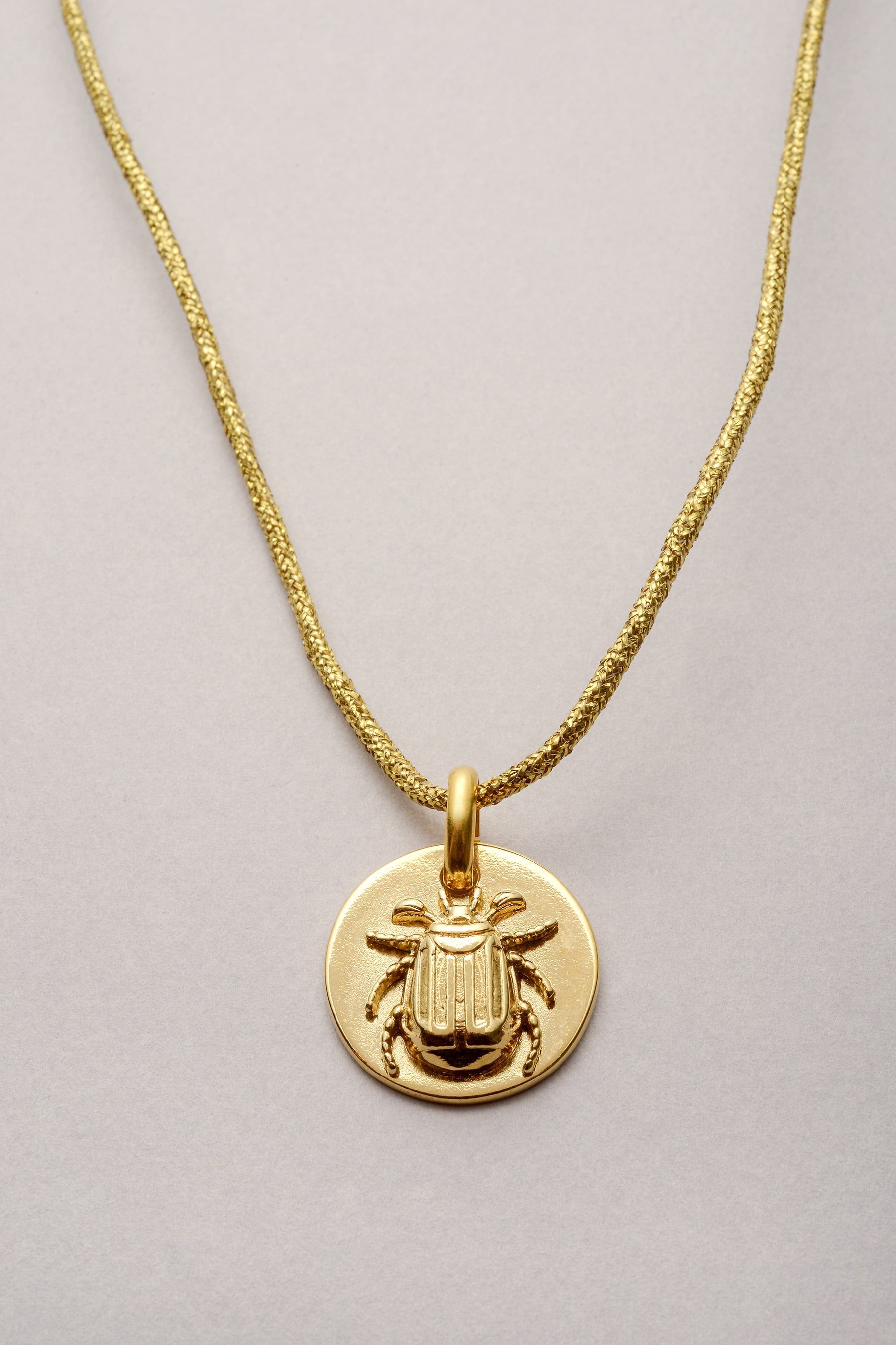 Ce bijou est composé d'un cordon de coton coloré et d'un pendentif scarabée doré. Le pendentif est une médaille avec un scarabée en relief : il a té soudé puis recouvert d'or dessus. 