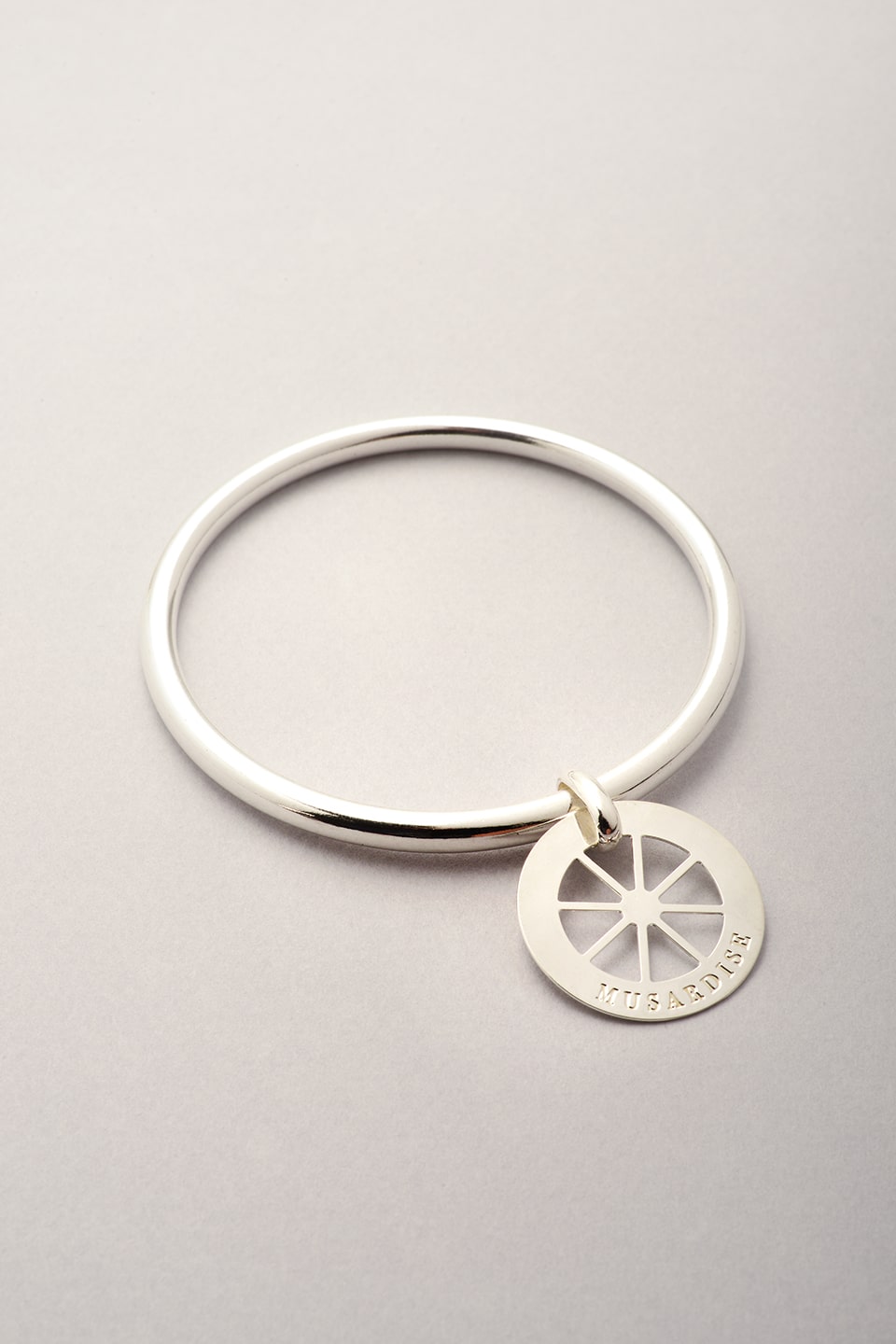 Bracelet jonc argenté avec un pendentif roue évidé. Jonc argenté pour femme fantaisie. Bijou fabriqué en France. 