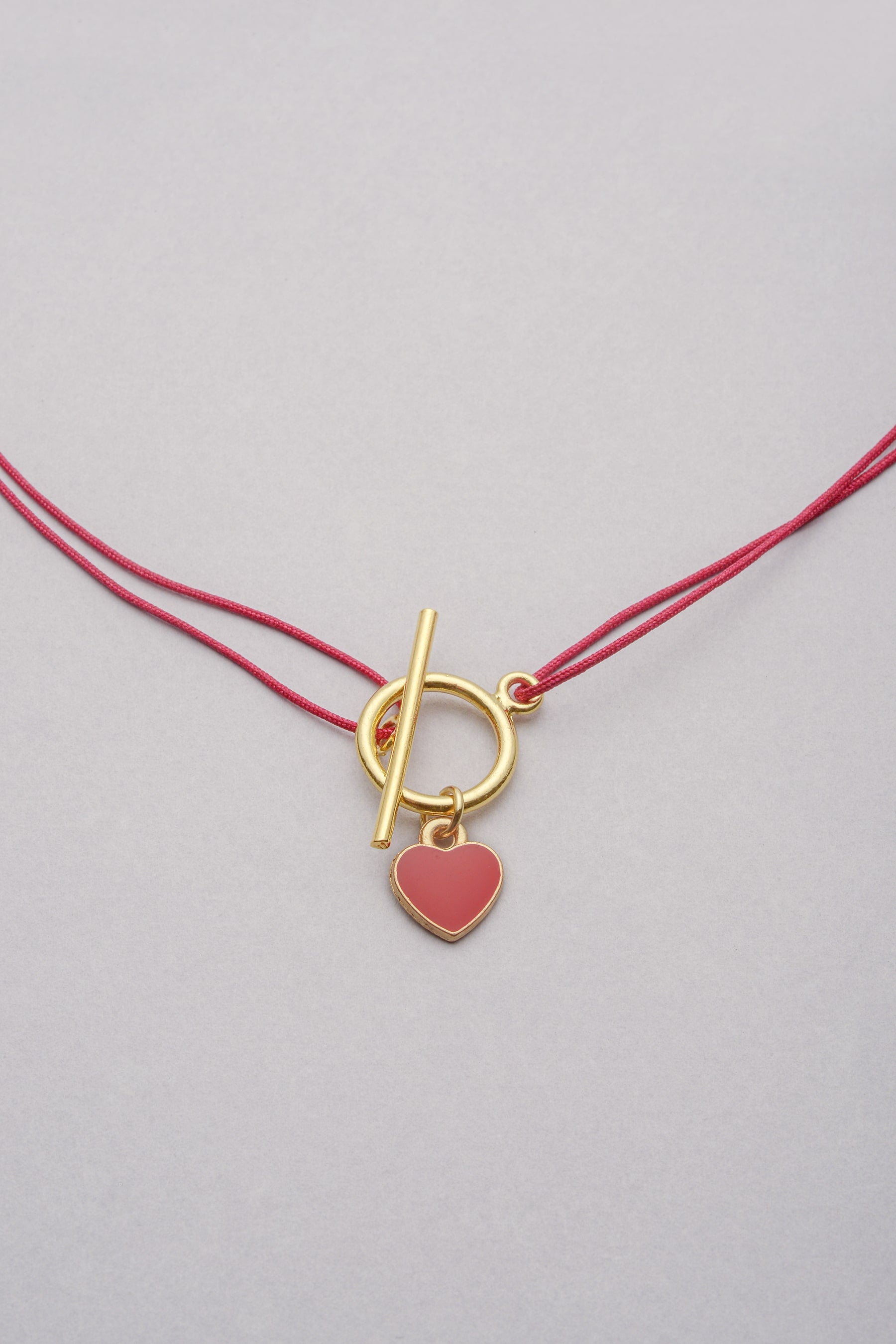 Le Collier Lou Cœur coloré doré se compose d’un cordon fin ajustable.