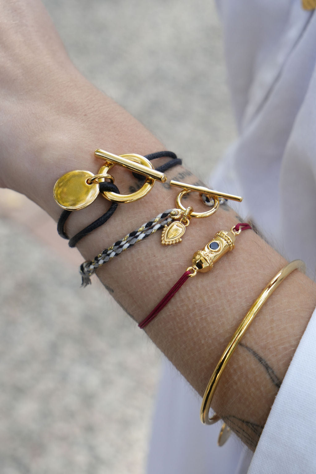 Bracelet attache médaille doré porté au poignet, cordon noir