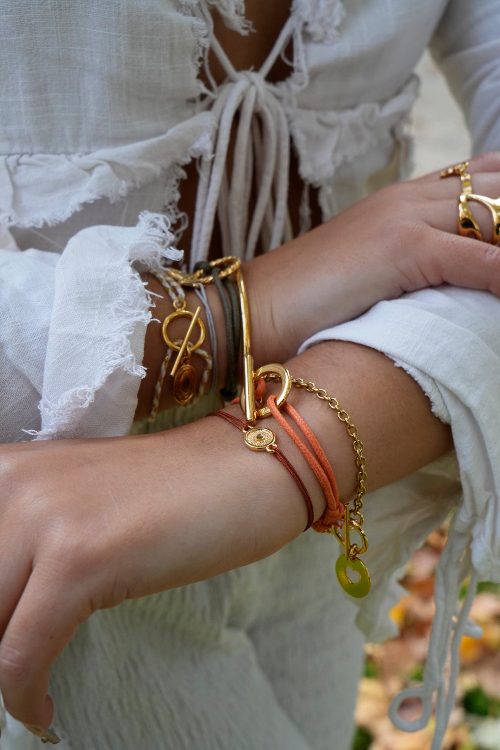 Bracelet fermoir T doré porté au poignet, cordon orange