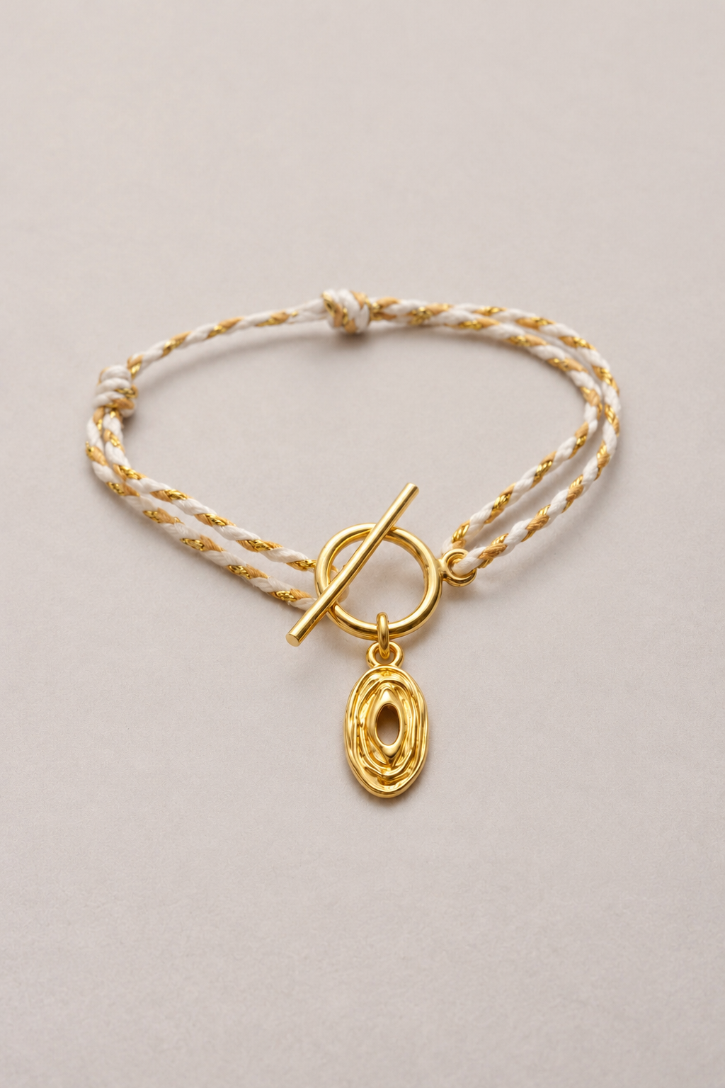 Bracelet Lou Hazel tressé doré, cordon blanc et doré et pendentif ovale ajouré