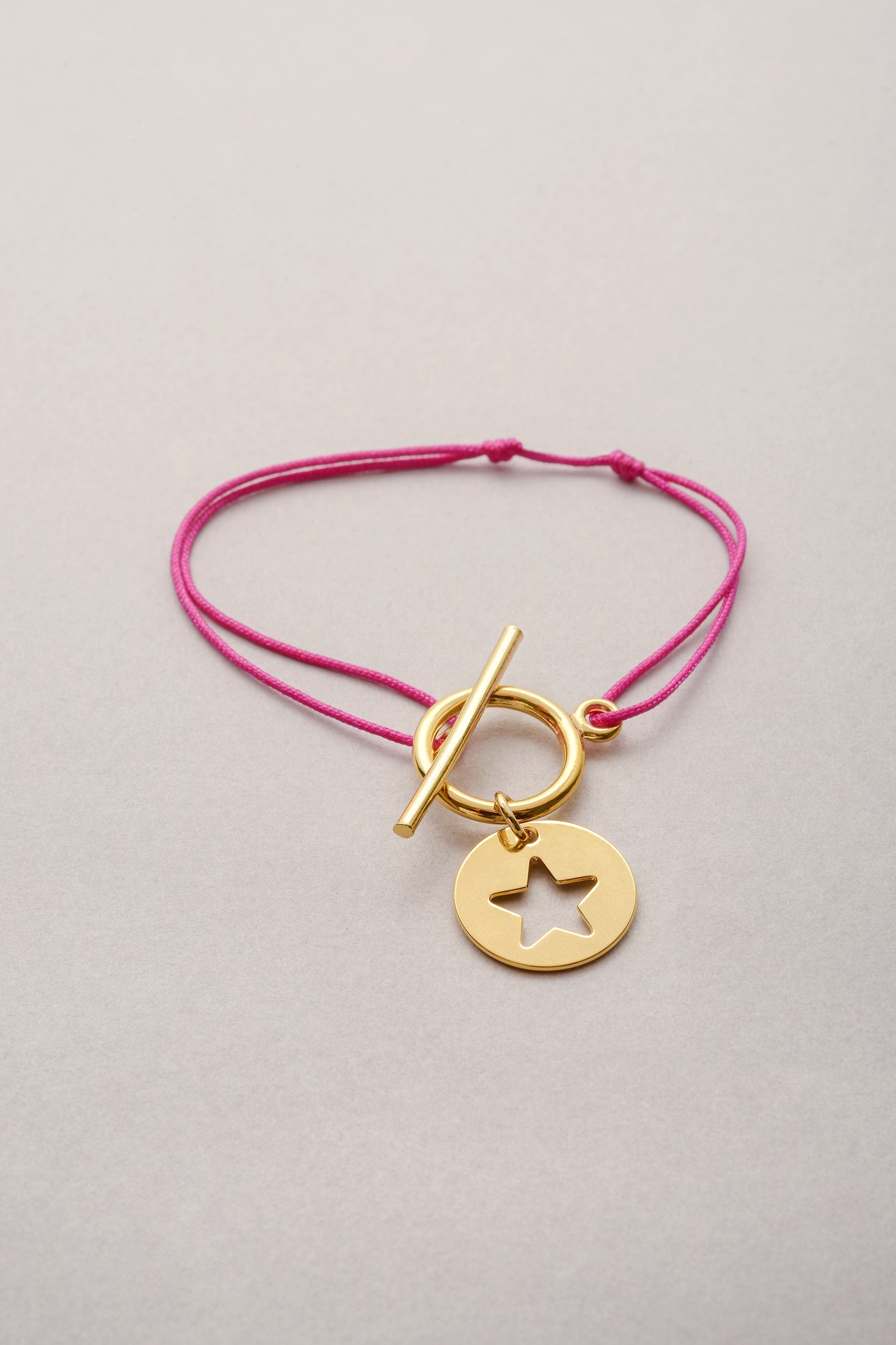 e bracelet Lou Médaille étoile doré est un bijou fantaisie composé d’une médaille en forme d'étoile argentée et  montée sur un cordon réglable grâce à deux nœuds coulissants. 