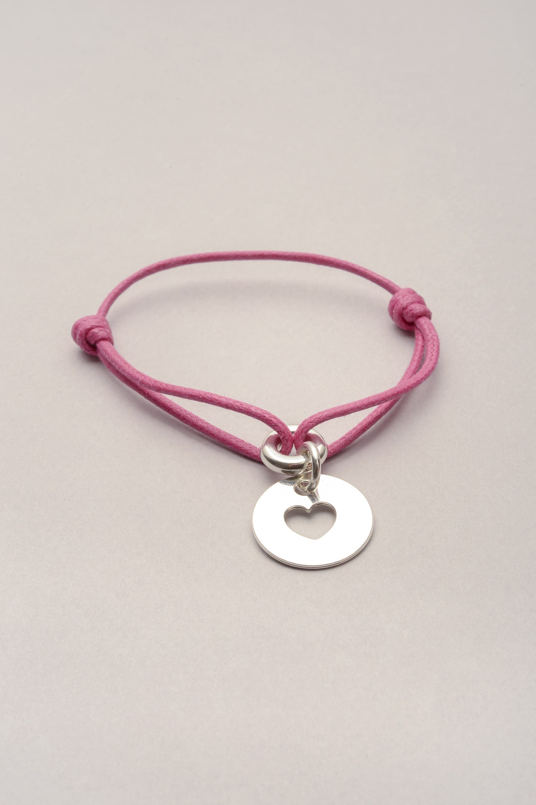 Ce bracelet est composé d'un cordon de coton coloré et d'une médaille avec un coeur évidé. ce bijou argenté fantaisie est fabriqué en France et existe en doré. 