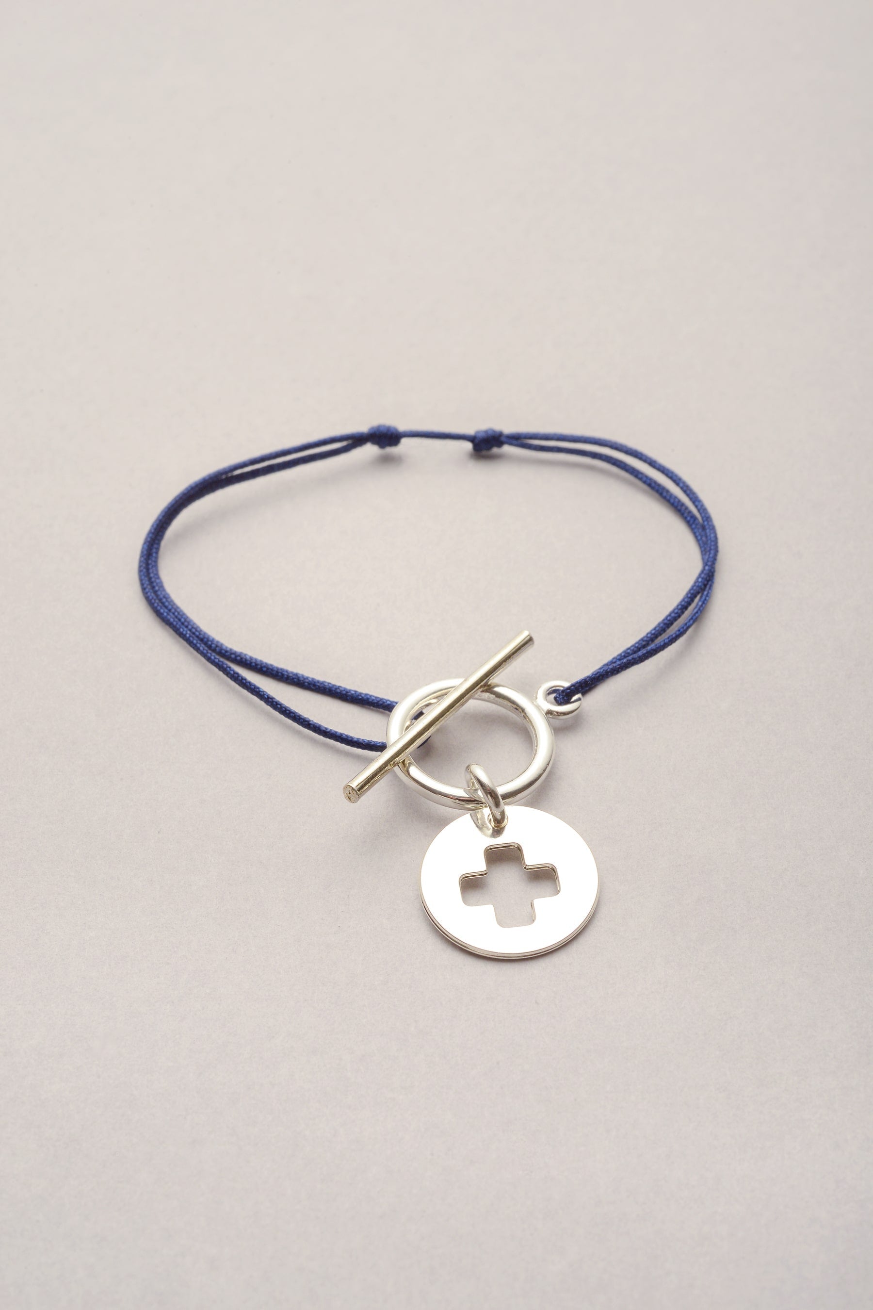Le bracelet Lou croix - Argenté et monté sur cordon fil fin coloré avec une médaille évidée en forme de croix