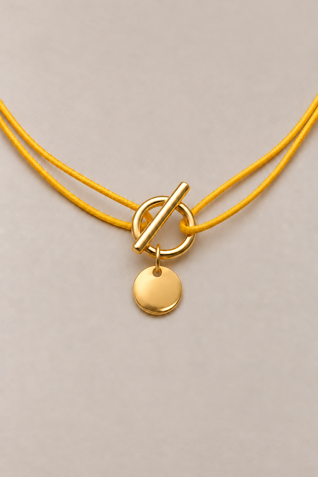 Collier attache médaille doré Musardise sur cordon jaune, médaille bombée et fermoir en T