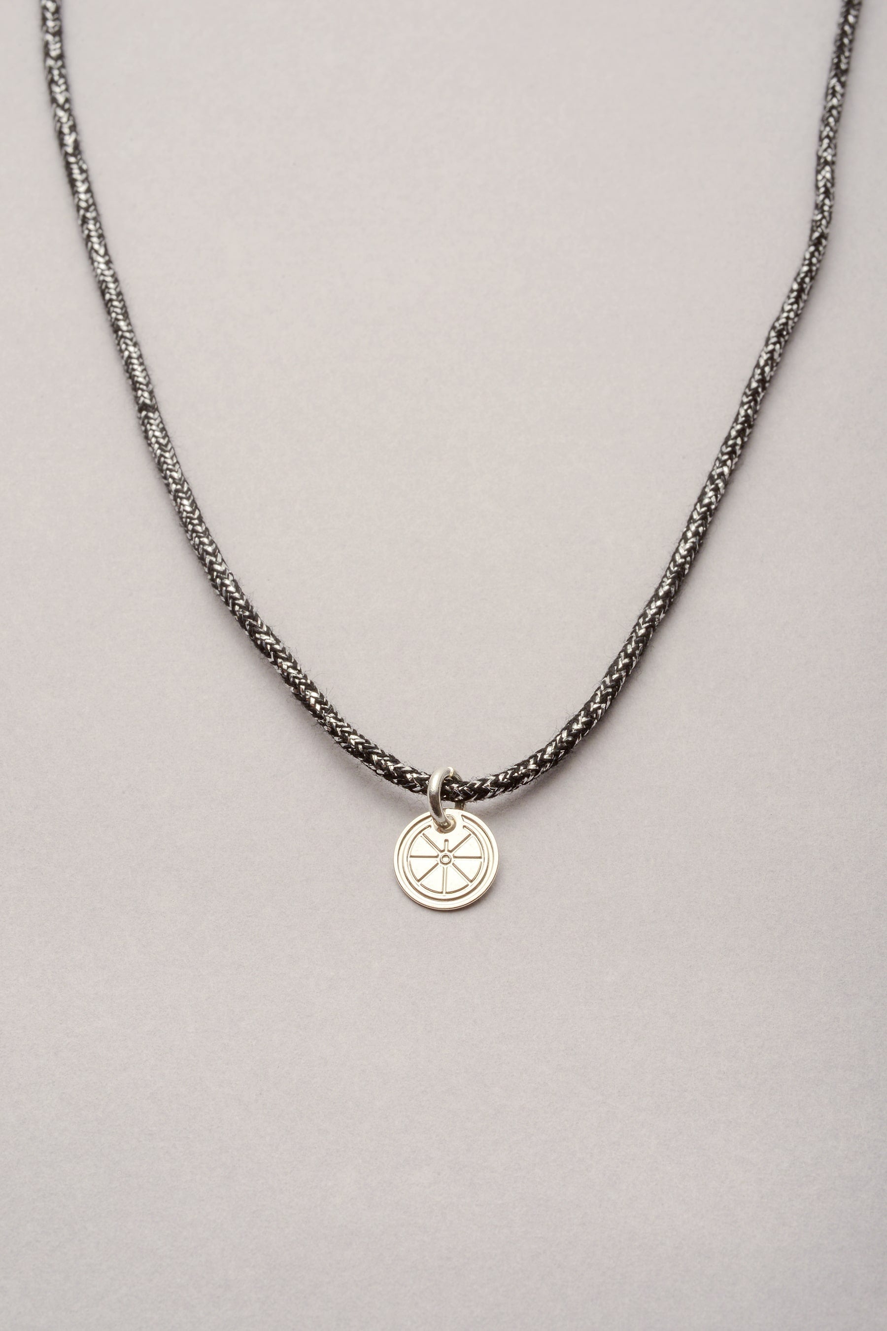 Collier composé d'un cordon simple avec une médaille de 10mm. Ce collier s'ajuste à la longueur de votre choix grâce à ses deux noeuds coulissants. 