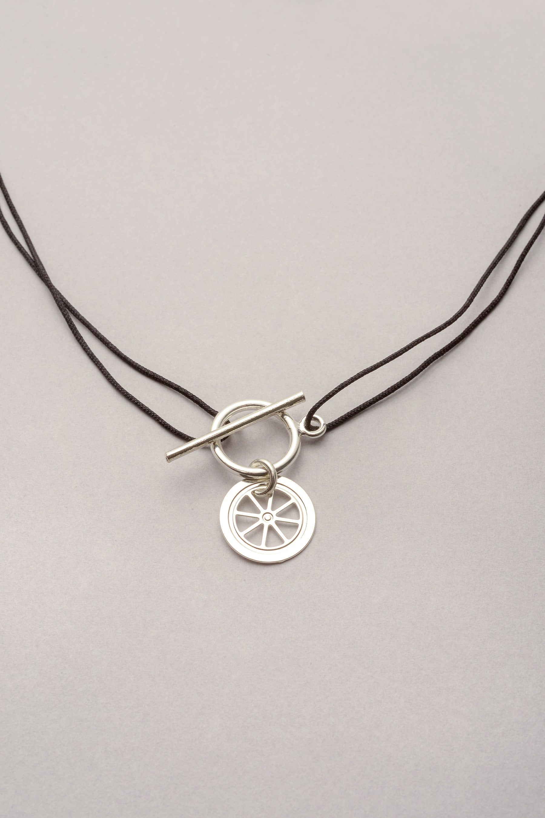 Collier roue Lou Musardise, bijou fantaisie français assemblé à la main dans l’atelier toulousain, avec pendentif roue argentée et cordon coloré personnalisable.