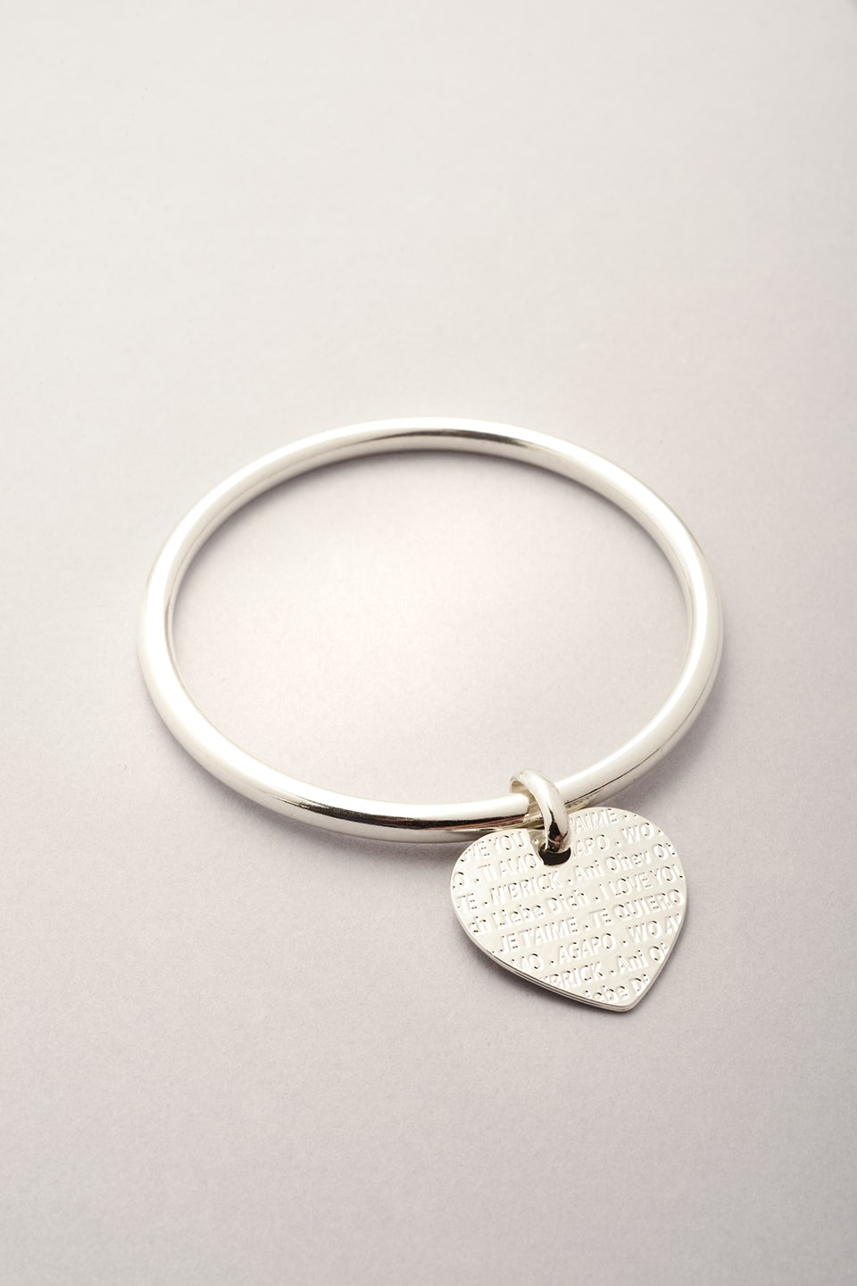 Ce jonc est composé d'un pendentif en forme de coeur sur lequel est gravé la phrase je t'aime en plusieurs langues. Bijou argenté pour femme. Création Musardise la bijouterie itinérante.