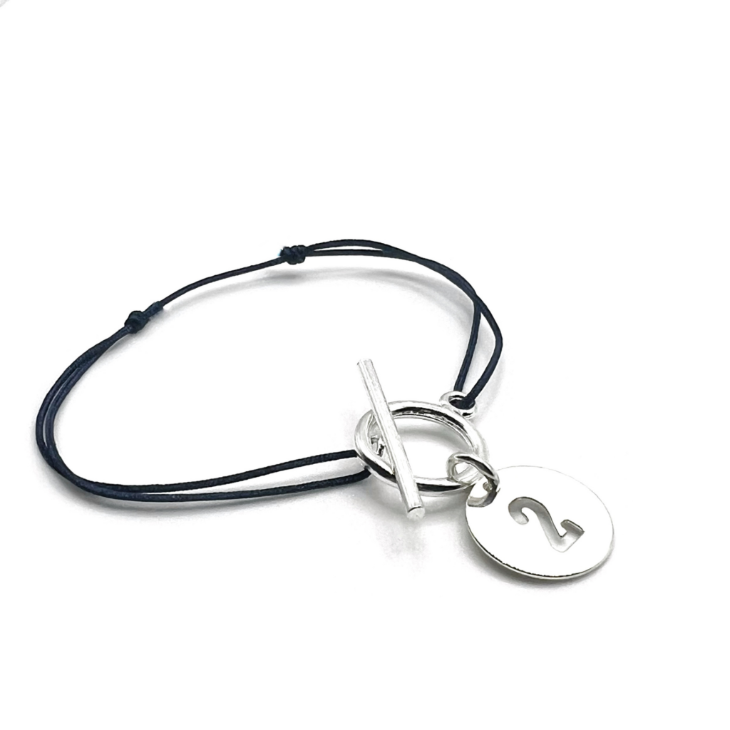 Bracelet avec un cordon fin et un pendentif chiffre porte bonheur. ce bijou pour femme est pratique avec son fermoir en T et ses noeuds coulissants. personnalisez le avec la couleur de votre choix ! Pas cher, c'est un cadeau idéal !