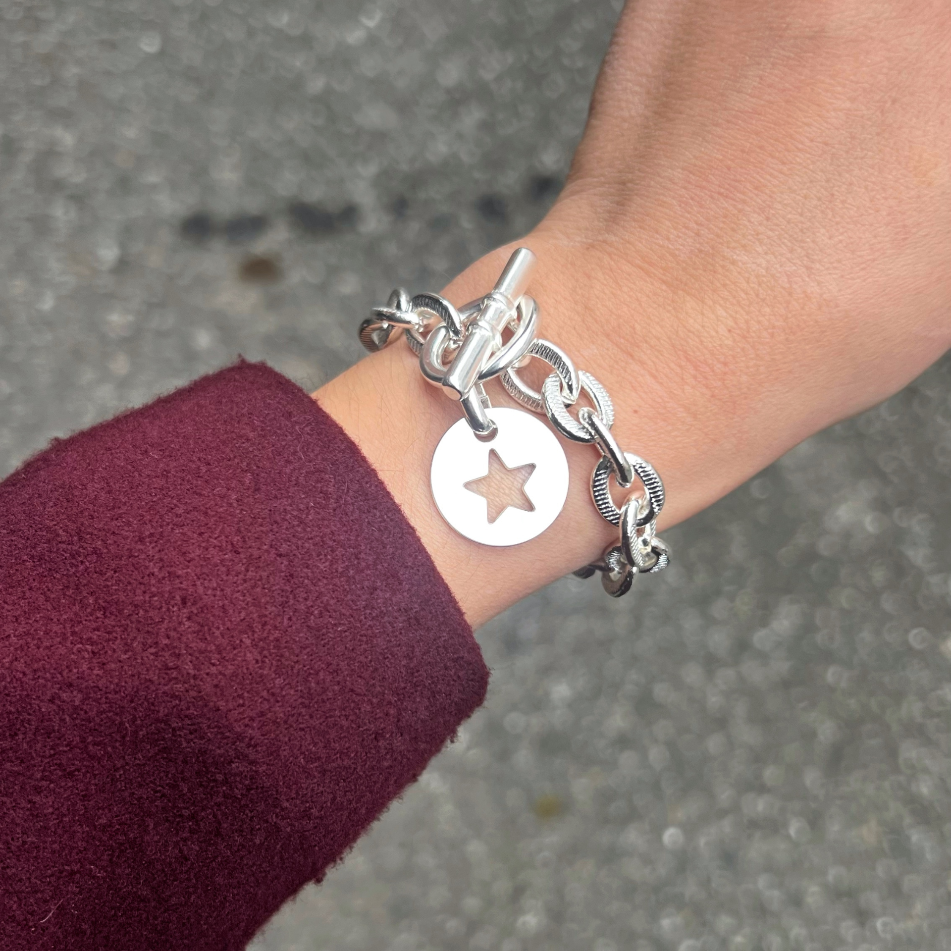 Bracelet scarlett étoile porté: ce bijou est composé d'une chaîne et d'un fermoir un T. Ce bracelet peut etre personnalisé avec plusieurs pendentifs différents.