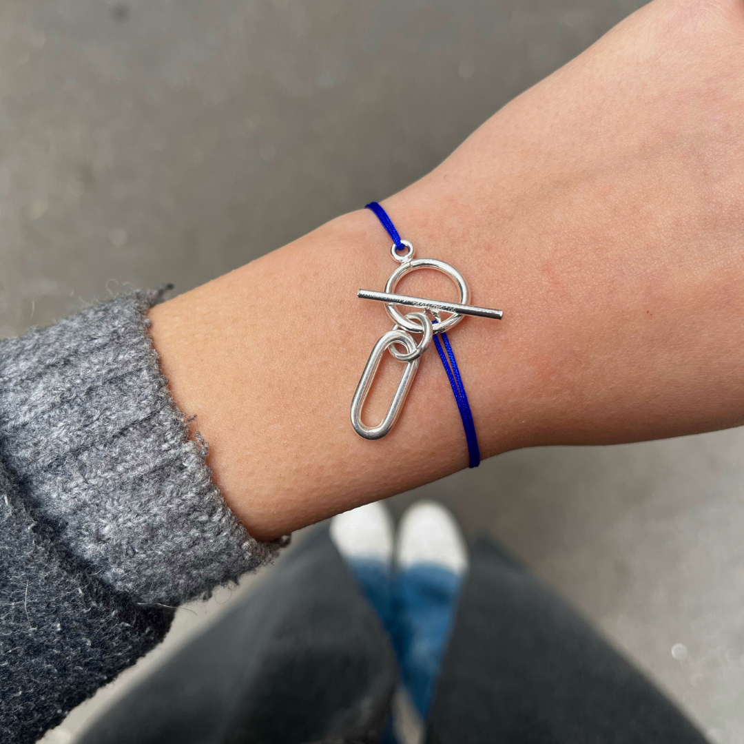 Bracelet cordon fin bleu électrique, son attache argentée ainsi qu'une pampille rectangulaire