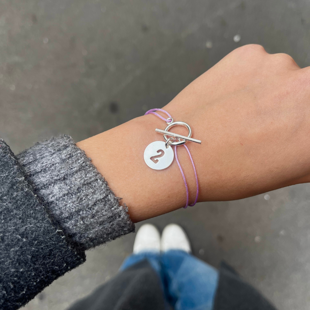 Bracelet cordon fin lilas, son attache argentée ainsi qu'une pampille chiffre numéro 2